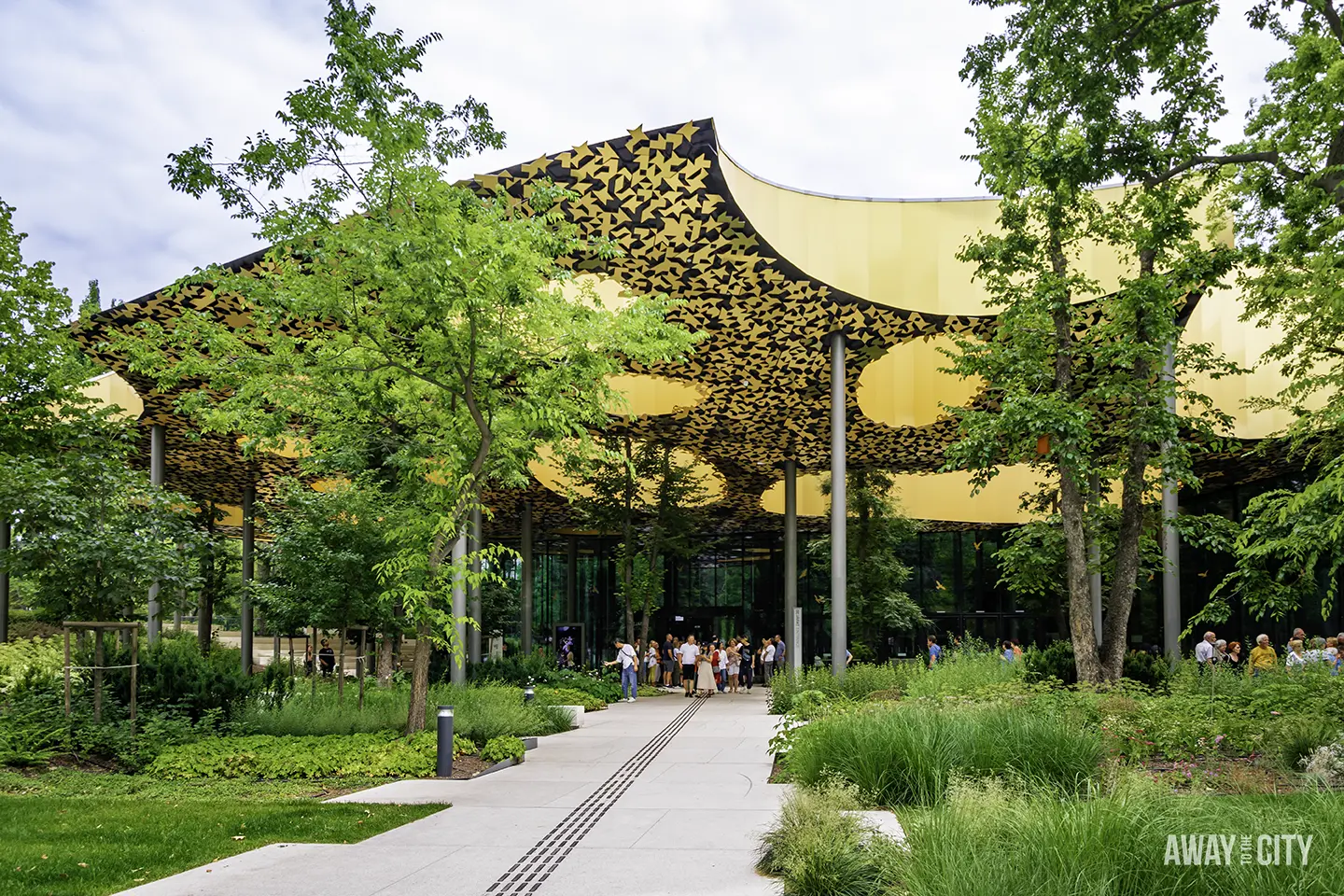 An exterior view of the House of Music's roof canopy and the pathway leading to the entrance of the building in Budapest City Park.