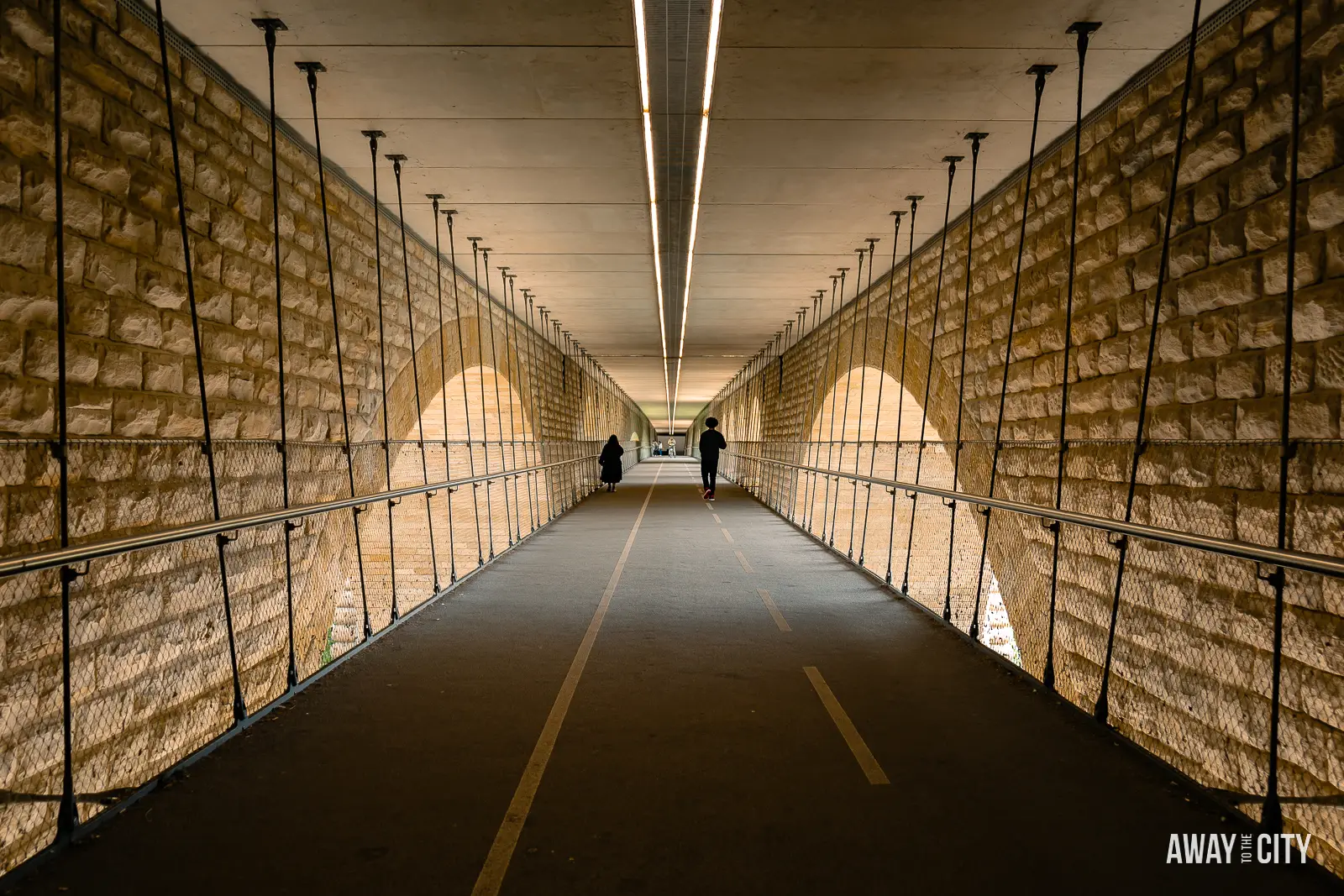 A picture of the lower deck's pedestrian and bicycle walkway of Adolphe Bridge in Luxembourg City, with people strolling along