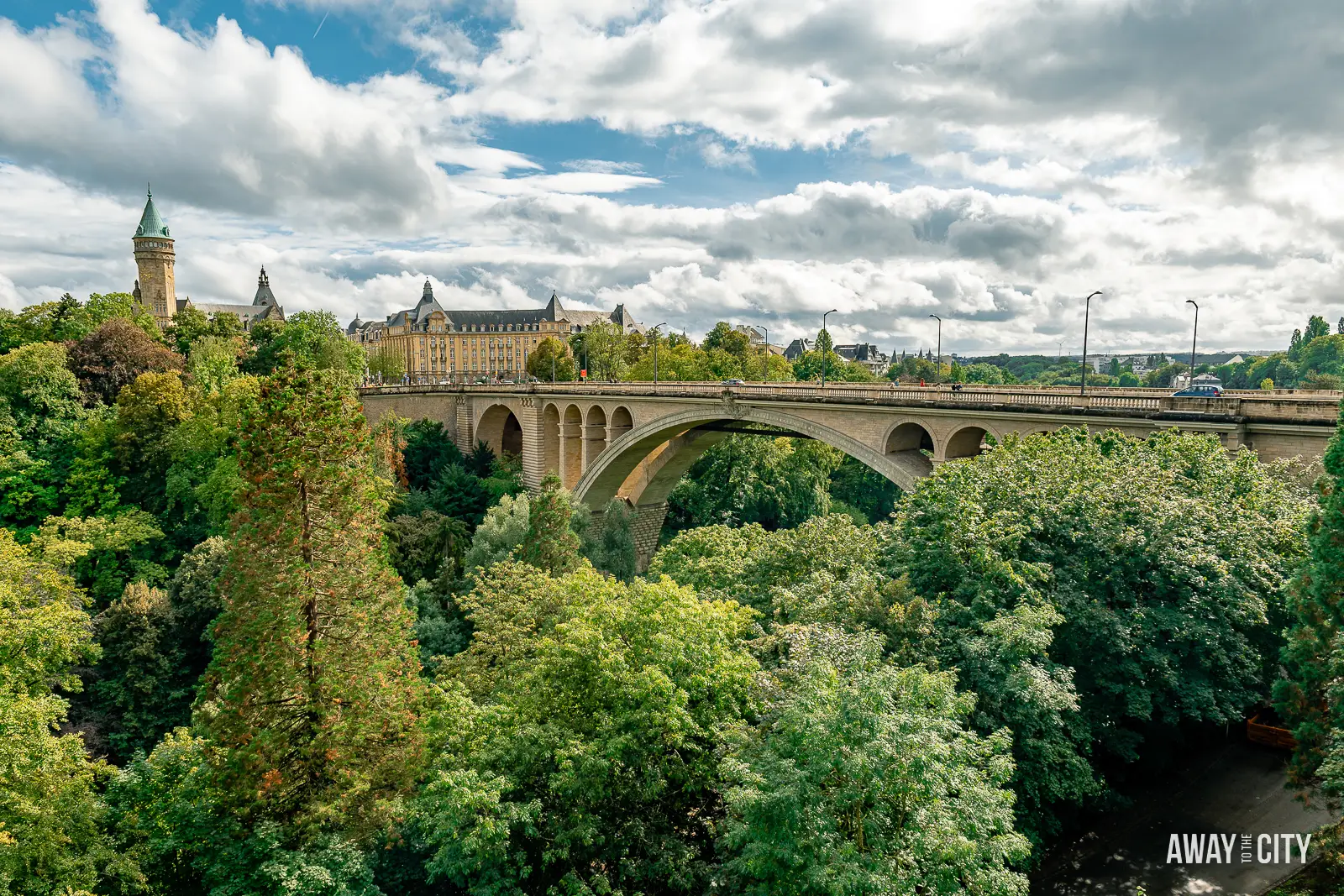 A picture of Adolphe Bridge crossing a river in Luxembourg City, with the Bourbon Plateau visible in the background