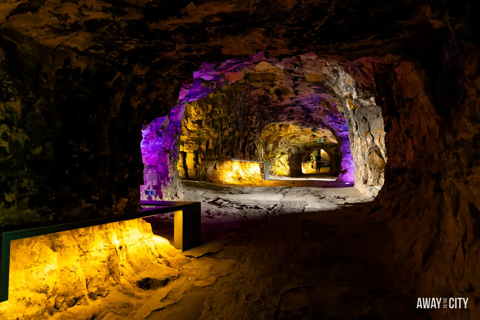 A picture of the dimly lit interior of a cave within the Bock Casemates in Luxembourg City, illuminated with purple and yellow lights