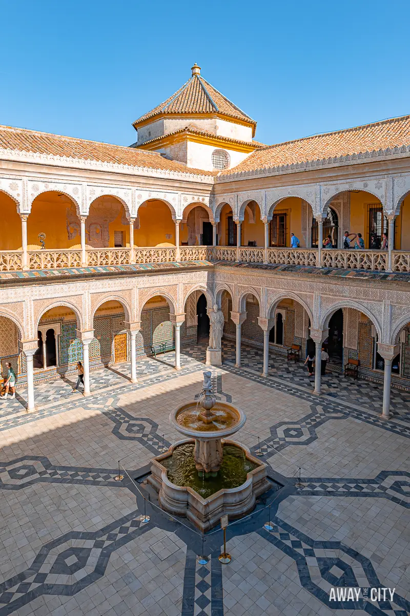 A picture of the main courtyard at Casa de Pilatos in Seville, featuring a fountain and tower.