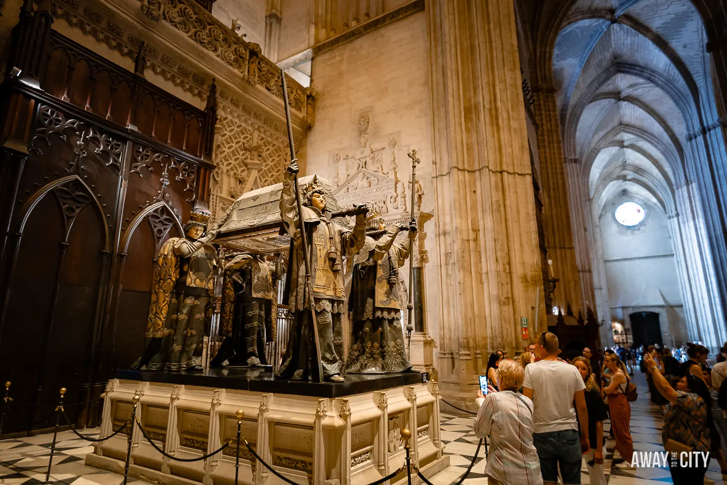 A group of people standing in front of the tomb of Christopher Columbus inside Seville Cathedral.
