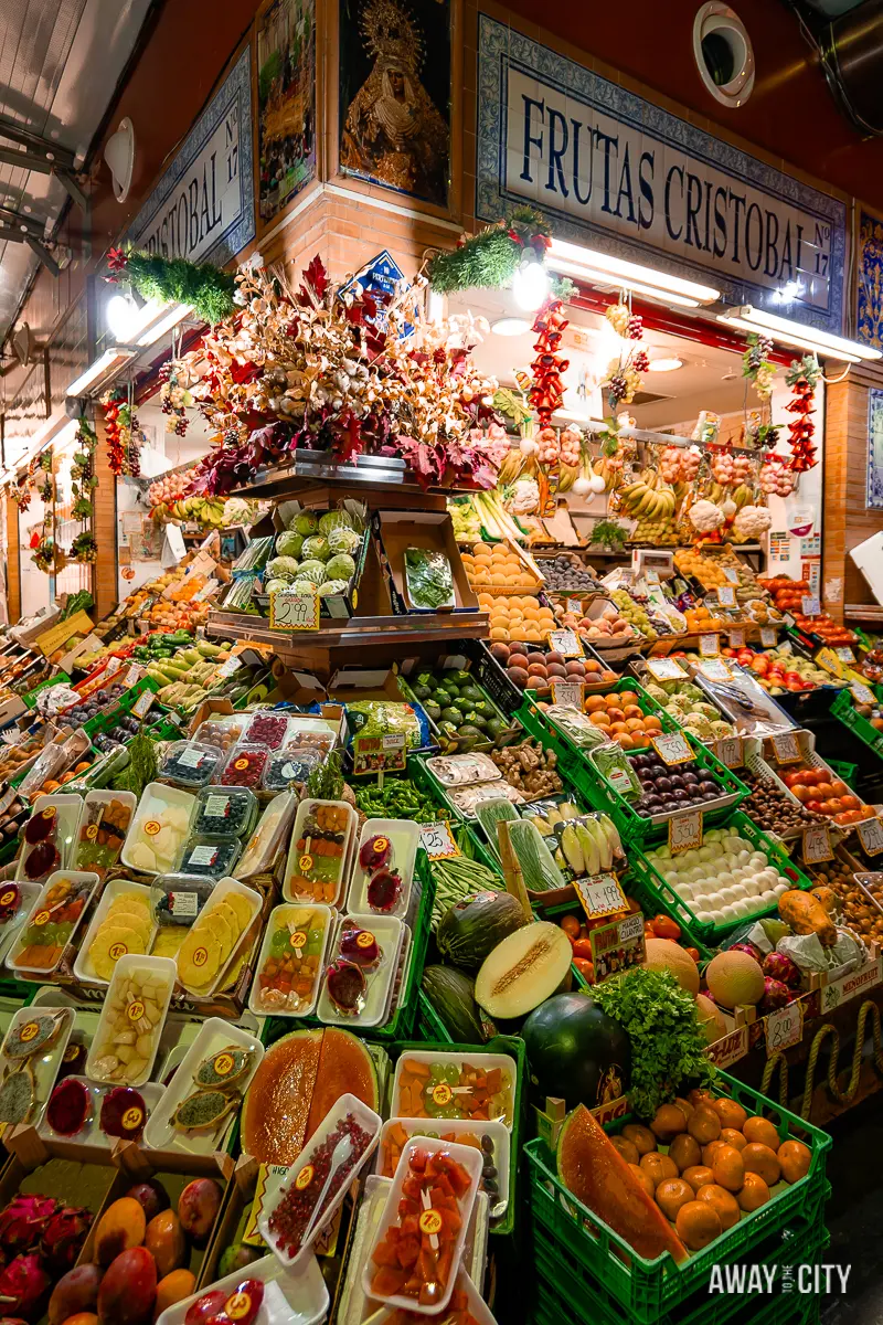A picture of a stall at Mercado de Triana in Seville, displaying a colourful array of fresh fruits and vegetables.