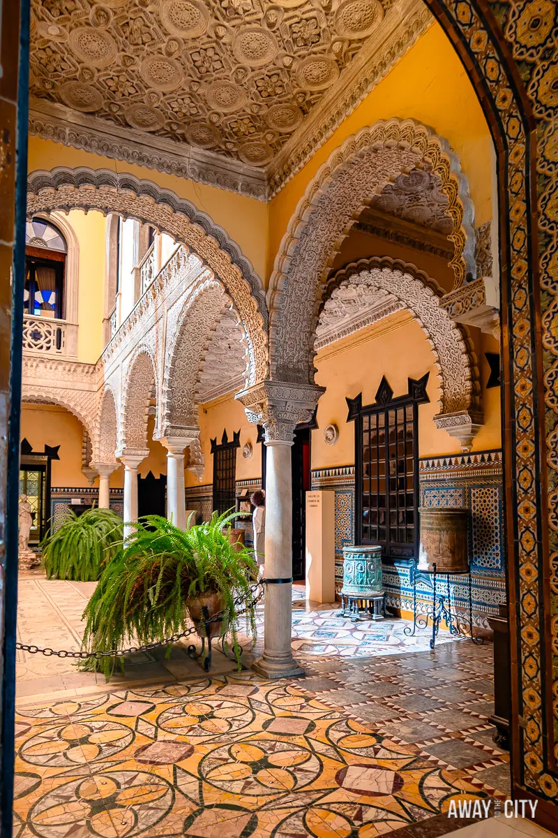 A picture of the inner courtyard of the Palace of the Countess of Lebrija in Seville, adorned with columns and plants.