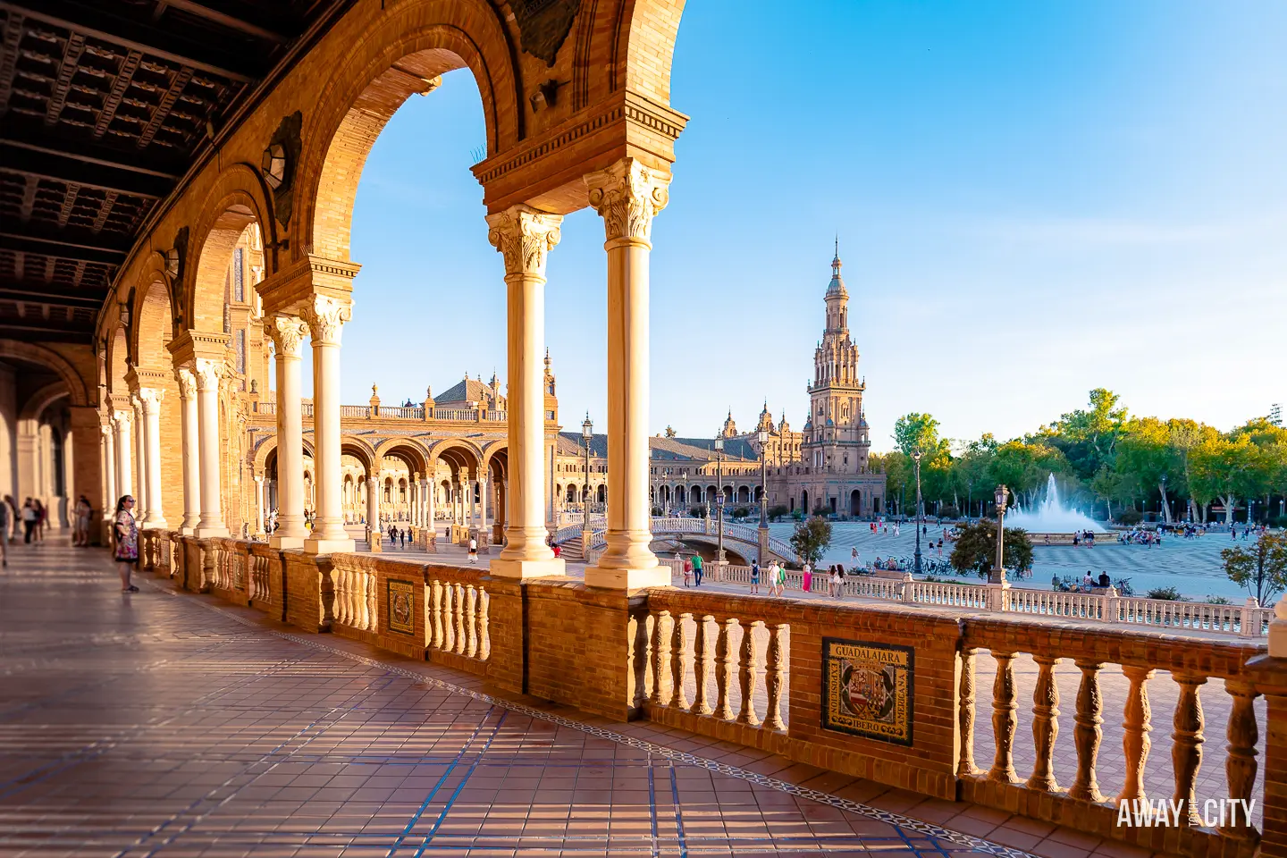 A picture of one of the hallways with its columns at Plaza de España in Seville (Spain) and a fountain in the background, captured during sunset.