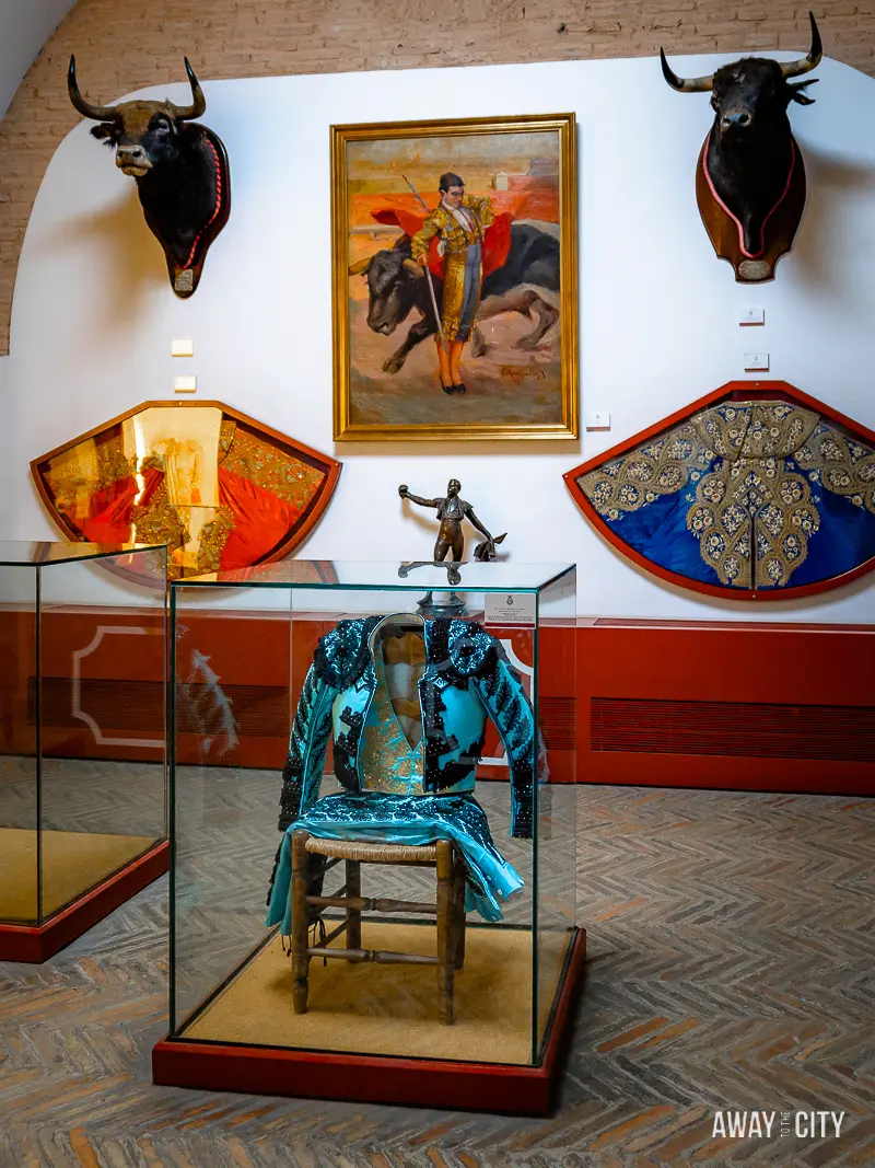 A picture of the museum section of Plaza de Toros Real Maestranza, displaying artefacts related to Spanish bullfighters, bulls, and matadors' clothing.