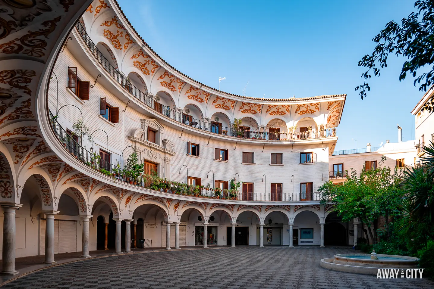 A picture of a courtyard with arches and windows of Plaza del Cabildo in Seville, with a small fountain.