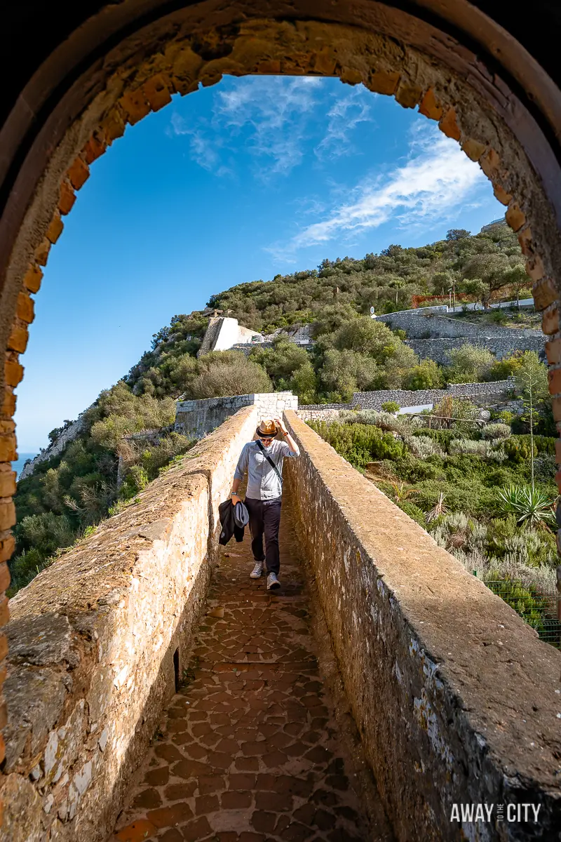 A picture through an archway onto the walkway with a person at the Moorish Castle in Gibraltar.