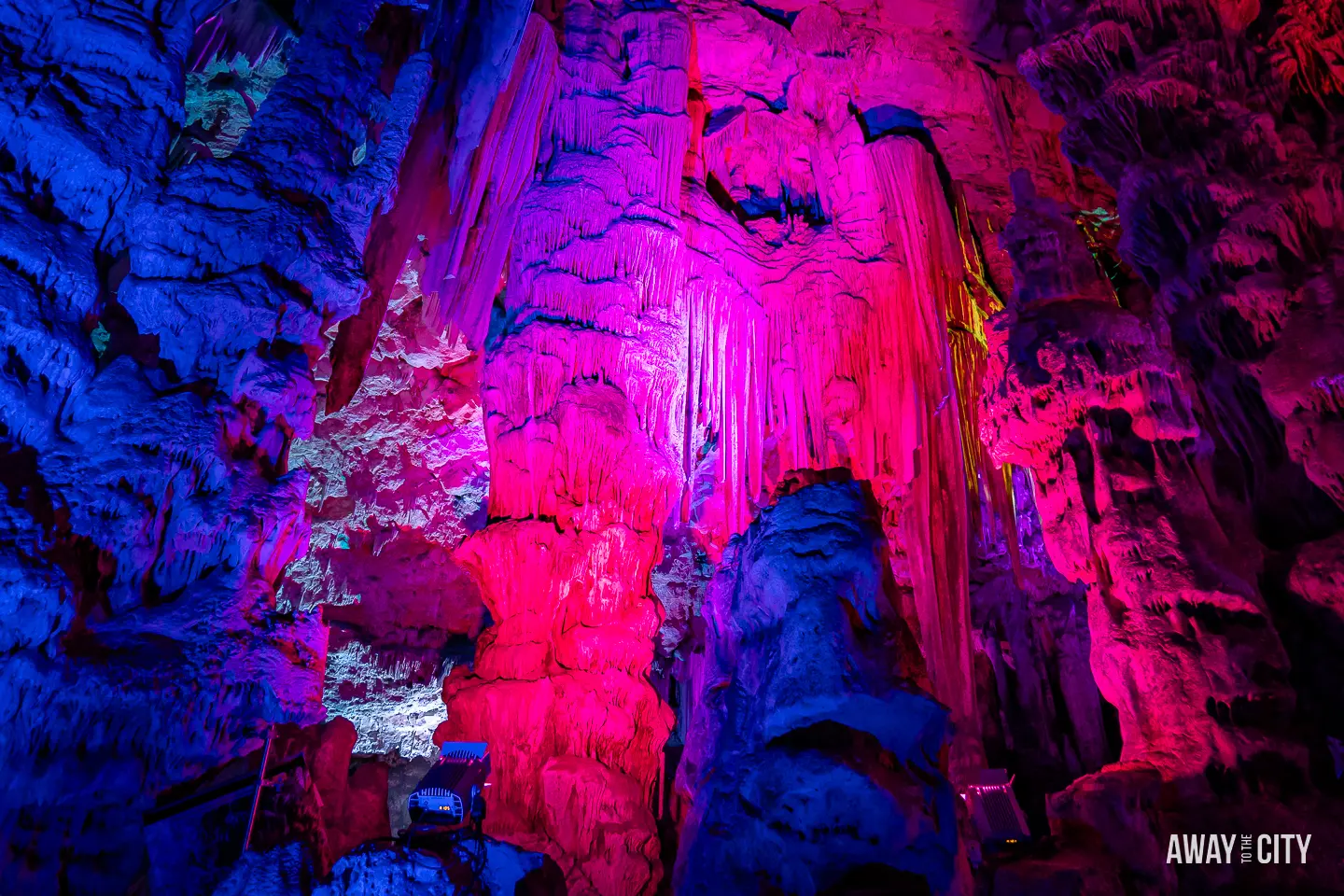 A picture of St. Michael's Caves in Gibraltar illuminated in red and purple hues, creating a mesmerising and atmospheric scene within the cave.