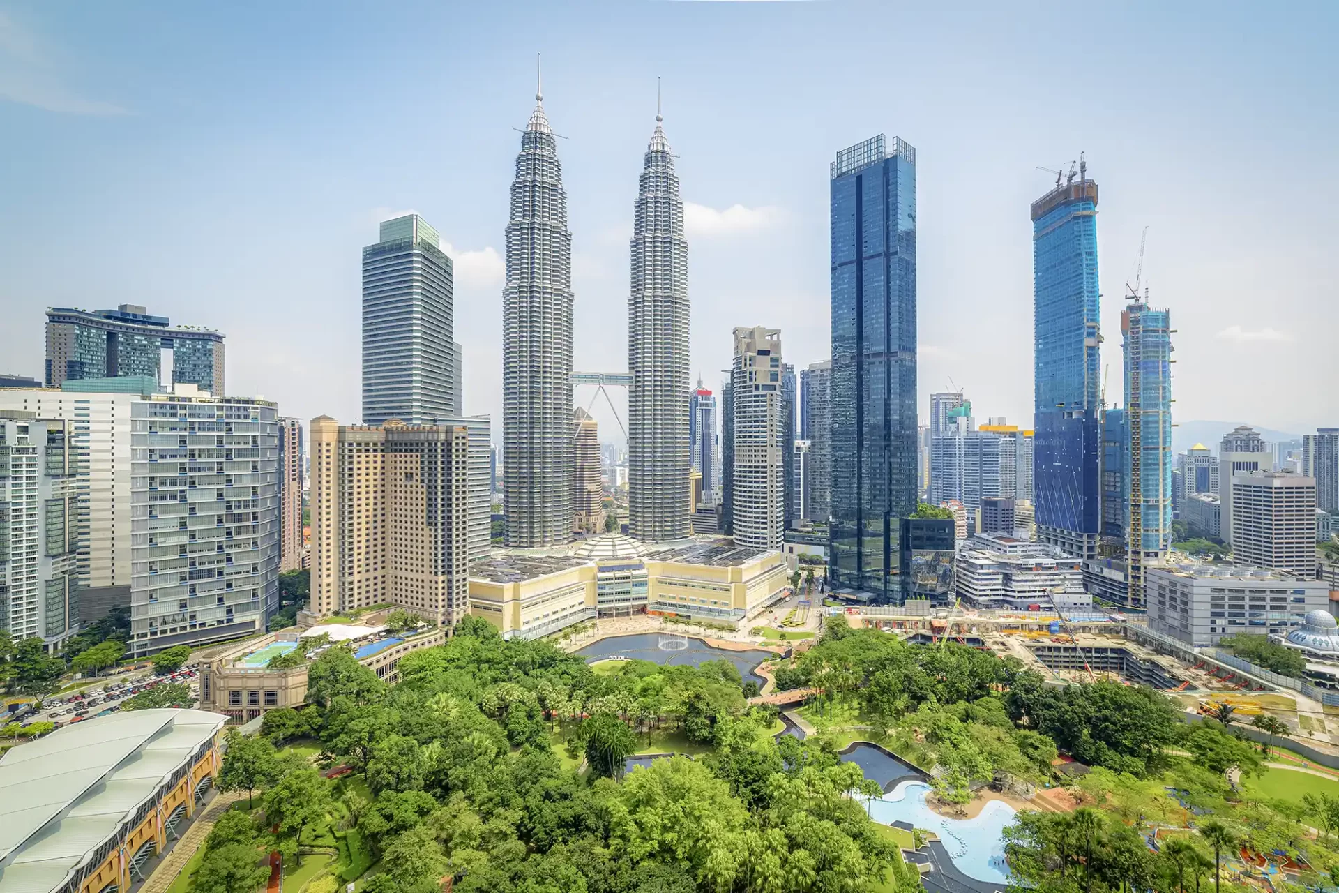 A panoramic view of Kuala Lumpur’s skyline, highlighted by the gleaming Petronas Towers amid a backdrop of skyscrapers and verdant greenery.