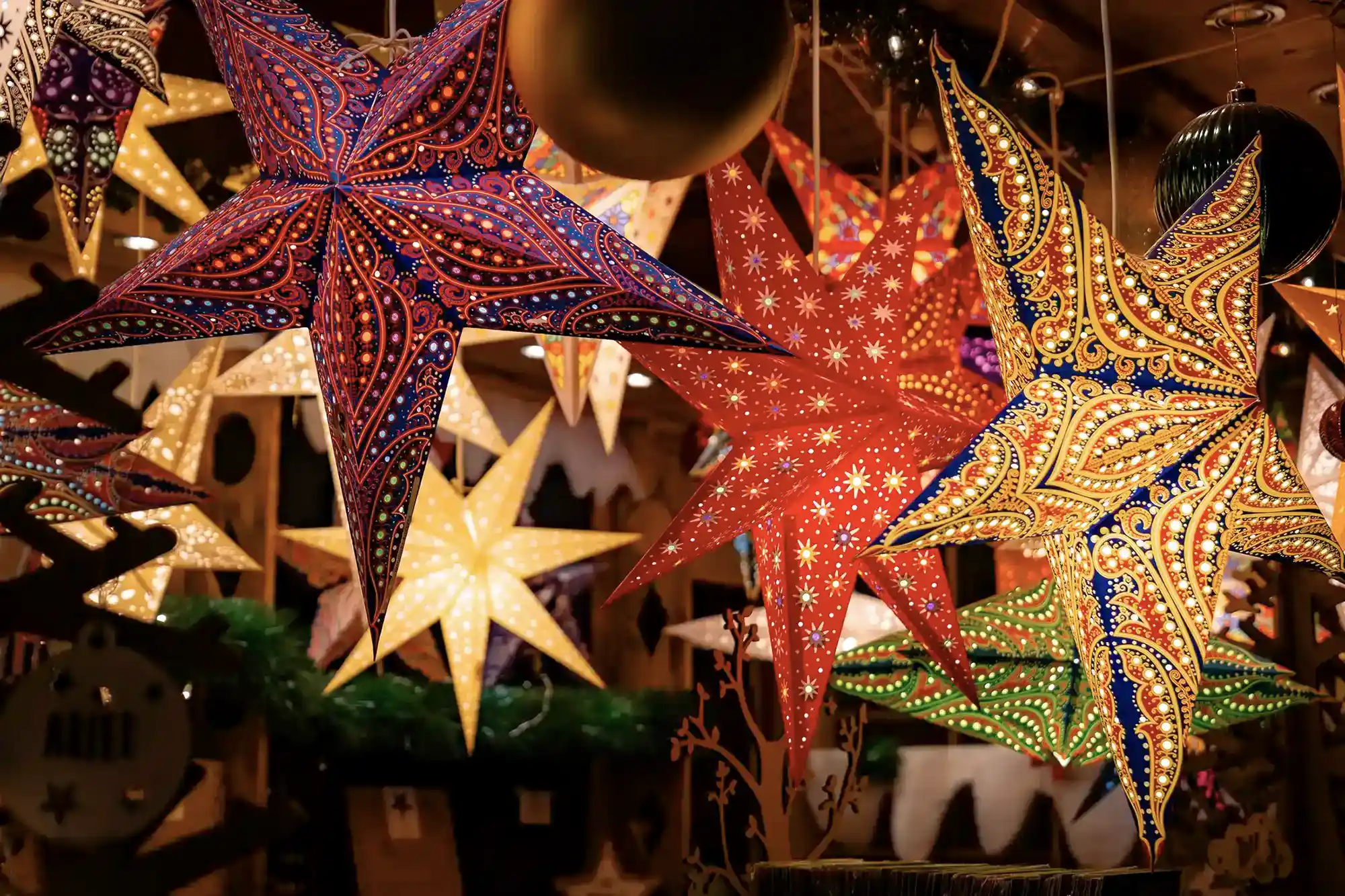 A picture of colourful paper LED stars hanging from a wooden chalet on New Street at Birmingham's Christmas Market.