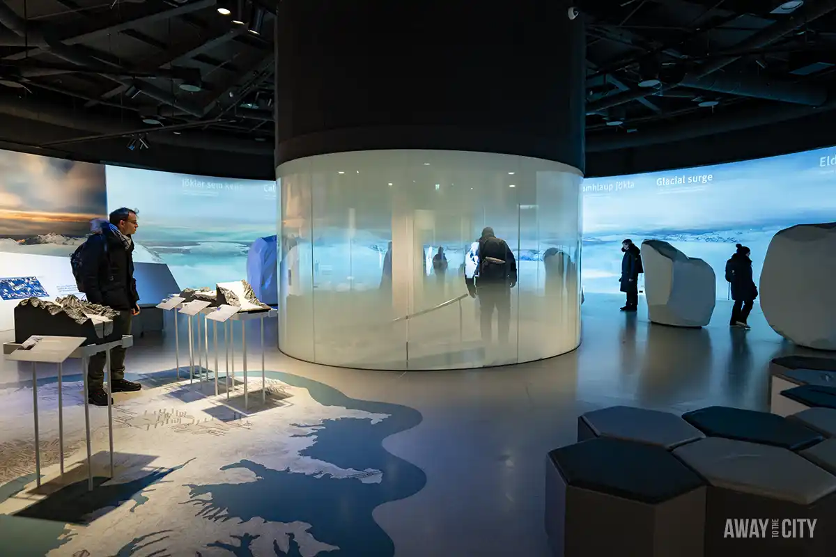 A room with a glass wall and people standing in front of a large screen at the Perlan museum in Reykjavik, one of the best things to do in Reykjavik in winter.