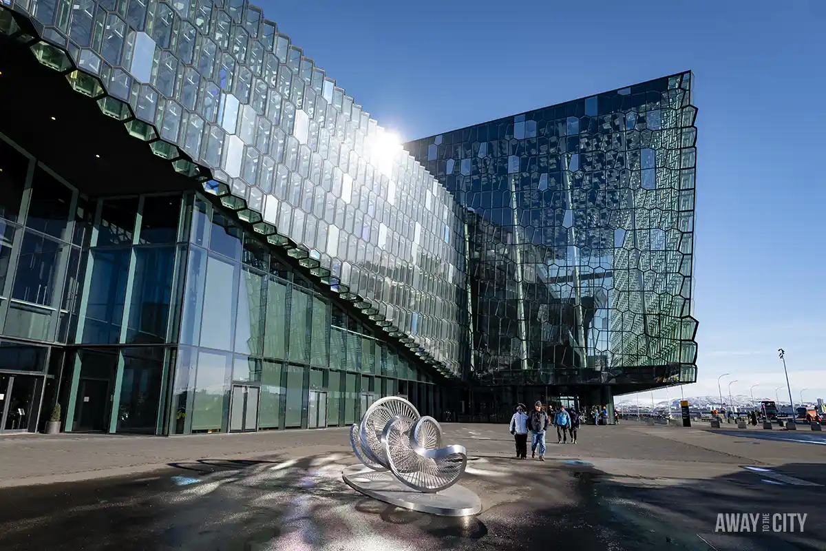 A group of people outside the Harpa concert hall and the “Aeolian harp” sculpture in front of the building in Reykjavik.