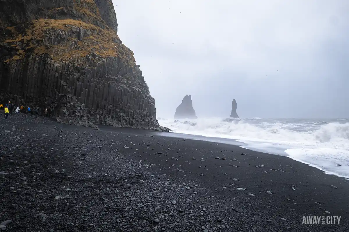 The Black Sand Beach of Reynisfjara in Iceland, known for its hexagonal basalt columns and large rock formations that rise out of the sea.