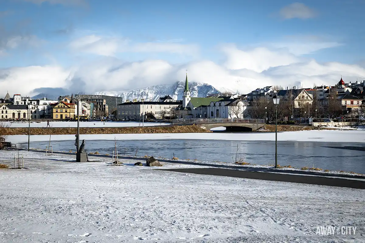 A snowy area with buildings at the Tjörnin Lake in Reykjavik, which is home to ducks and swans, especially beautiful when frozen in winter.