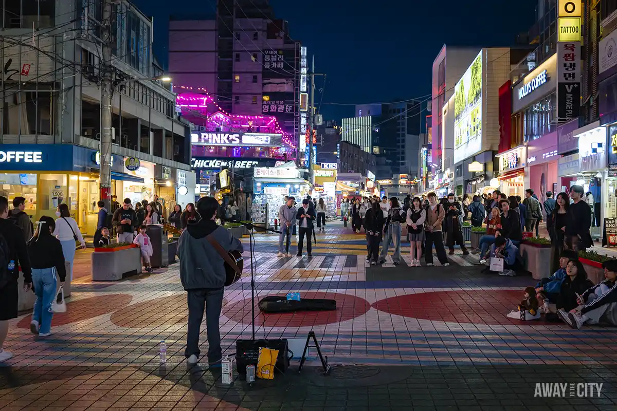 A busker on the busy Hongdae Street in Seoul, a hangout known for its neon-lit bars & clubs, restaurants, murals, fashion stores & street performers.