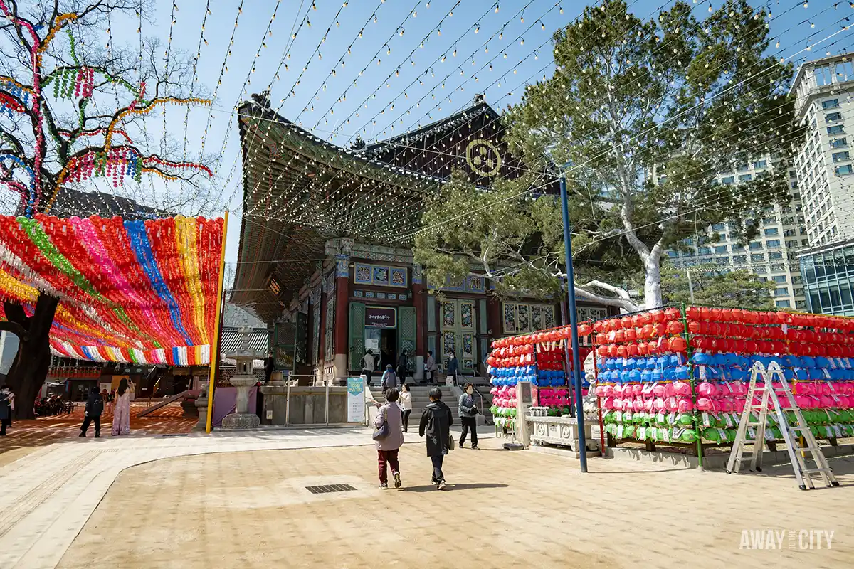 A group of people walking in front of Jogyesa Temple in Seoul, the main temple of the Jogye Order of Korean Buddhism.