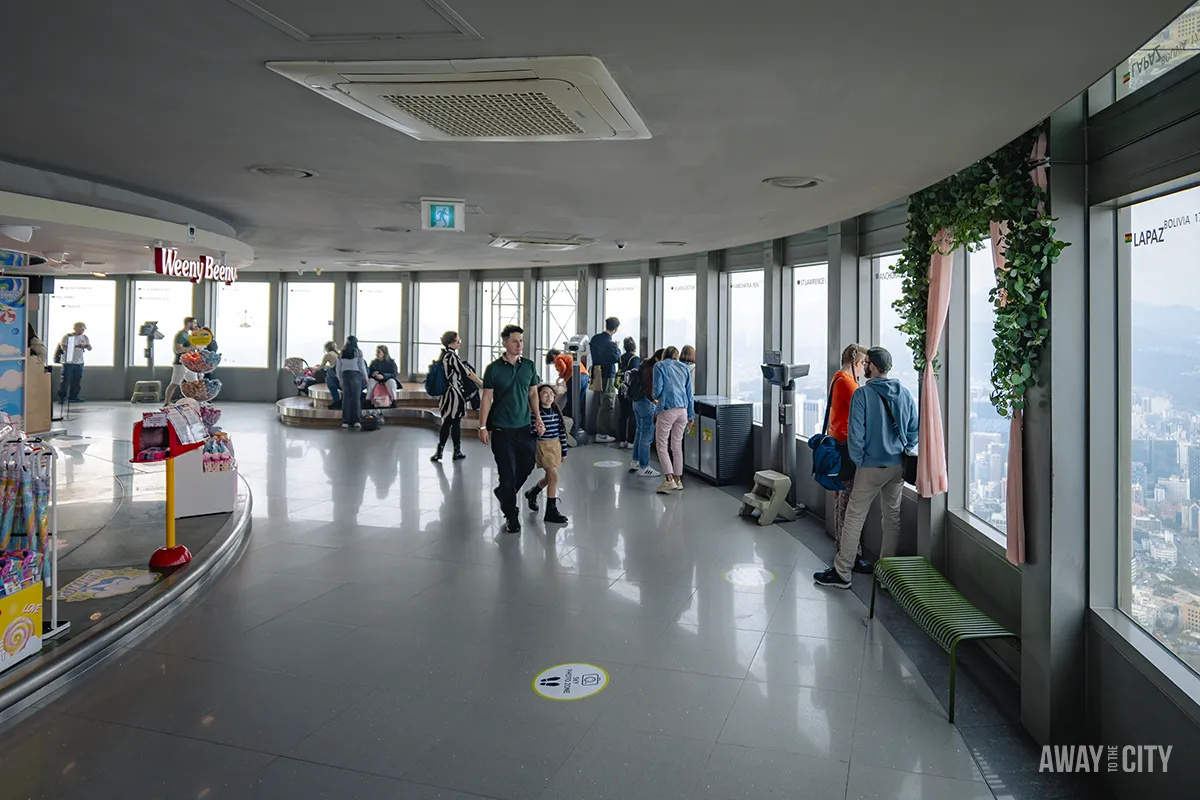 A group of people sitting at tables on one of the observatory floors of N Seoul Tower (Namsan Seoul Tower).