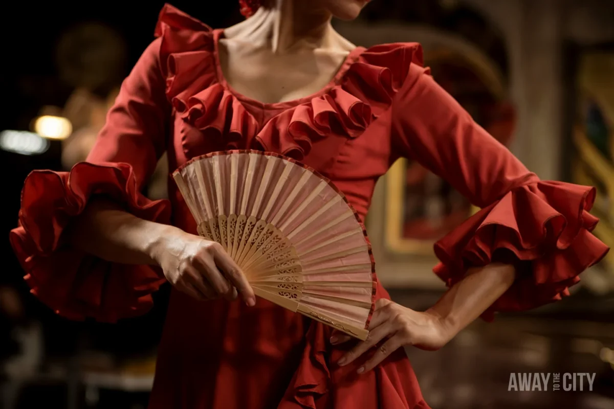 A woman in a vibrant red flamenco dress with ruffled sleeves holds a decorative fan, showcasing the traditional attire and elegance of the dance.
