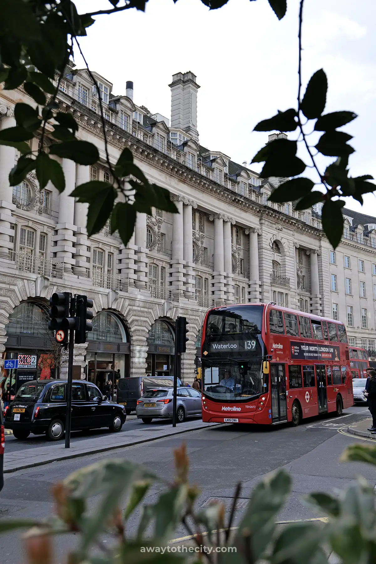 A classic red London double-decker bus passes in front of the grand architecture of Regent Street.