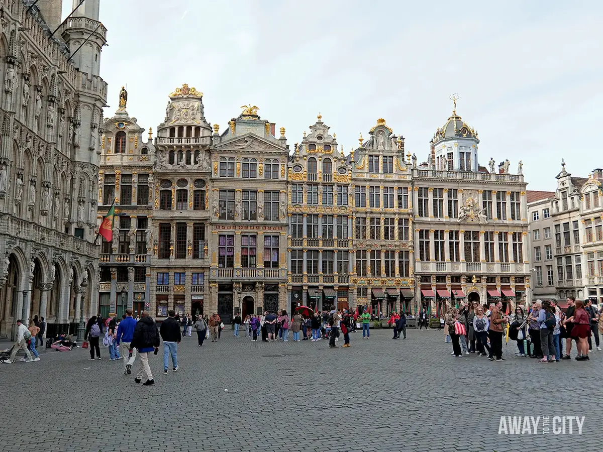 Grand Place Brussels with ornate gilded guildhall façades, cobblestone square and crowds of visitors gathered beneath historic buildings.