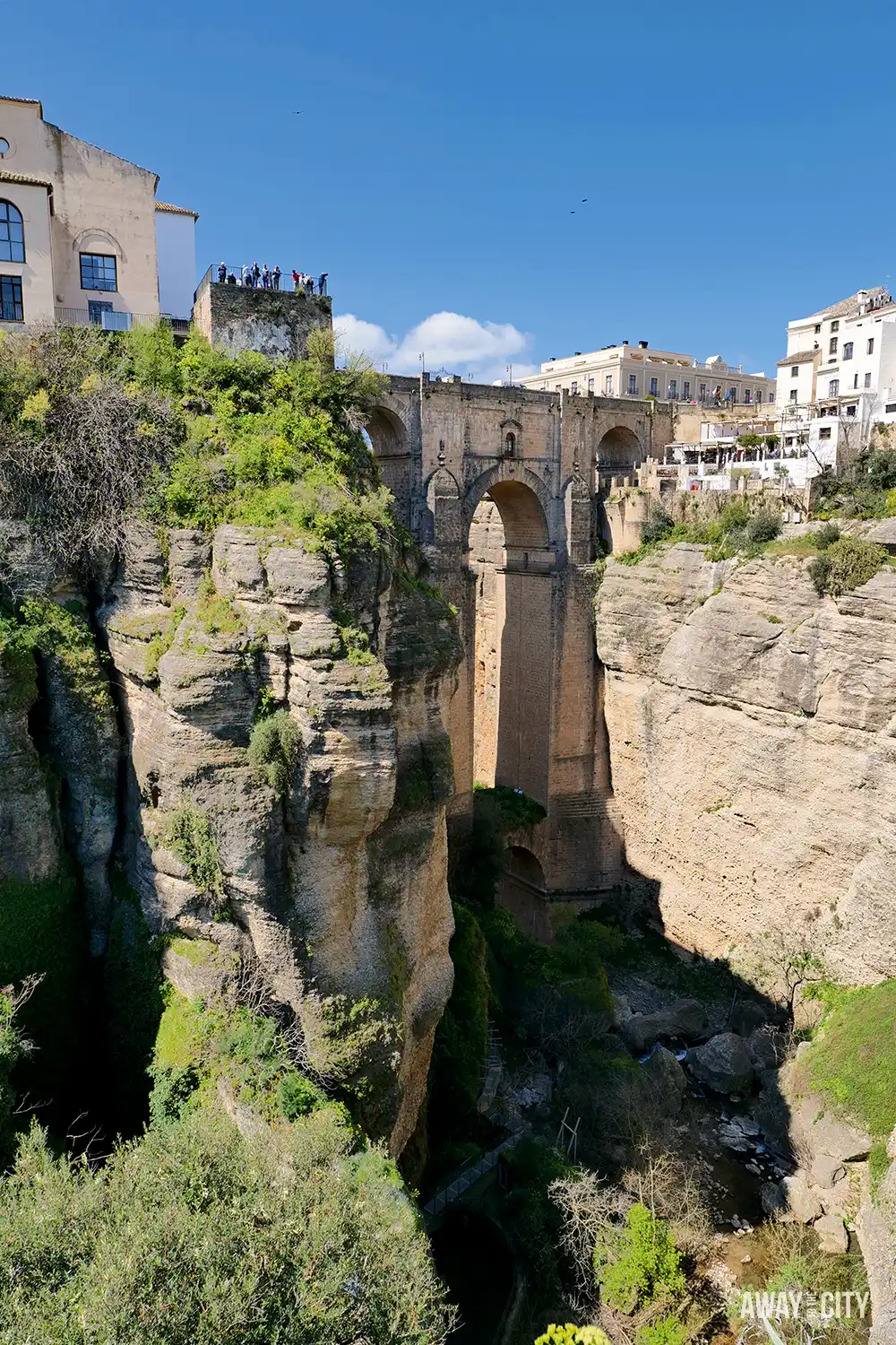 Puente Nuevo bridge in Ronda spanning a deep gorge, with dramatic cliffs, stone arches, and white buildings perched along the edge above.