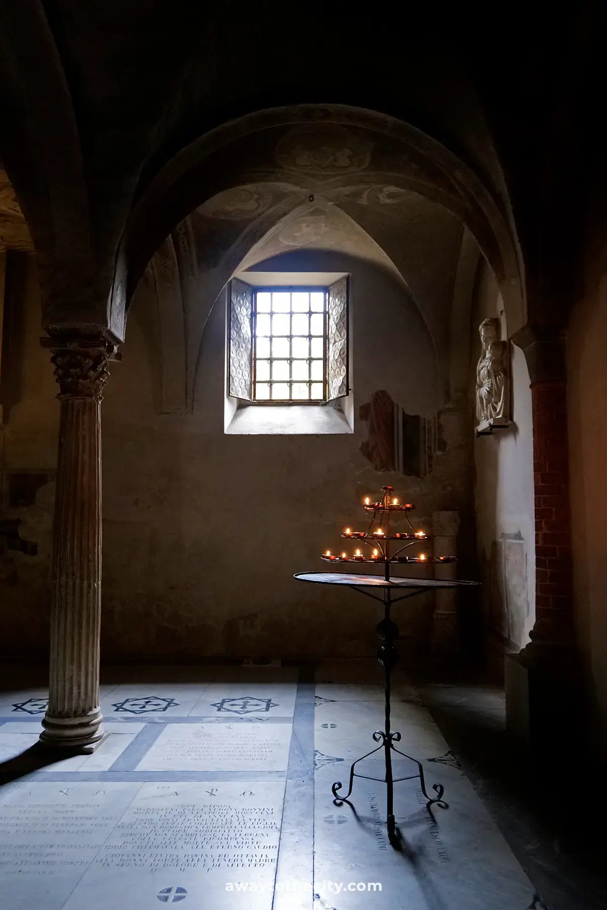 A multi-tiered candle stand glows softly inside the Basilica di San Miniato al Monte.