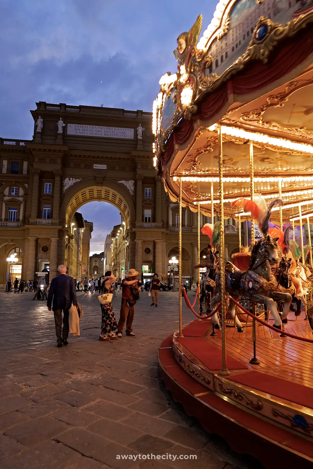 A vibrant carousel glows at night in Piazza della Repubblica in Florence, Italy.