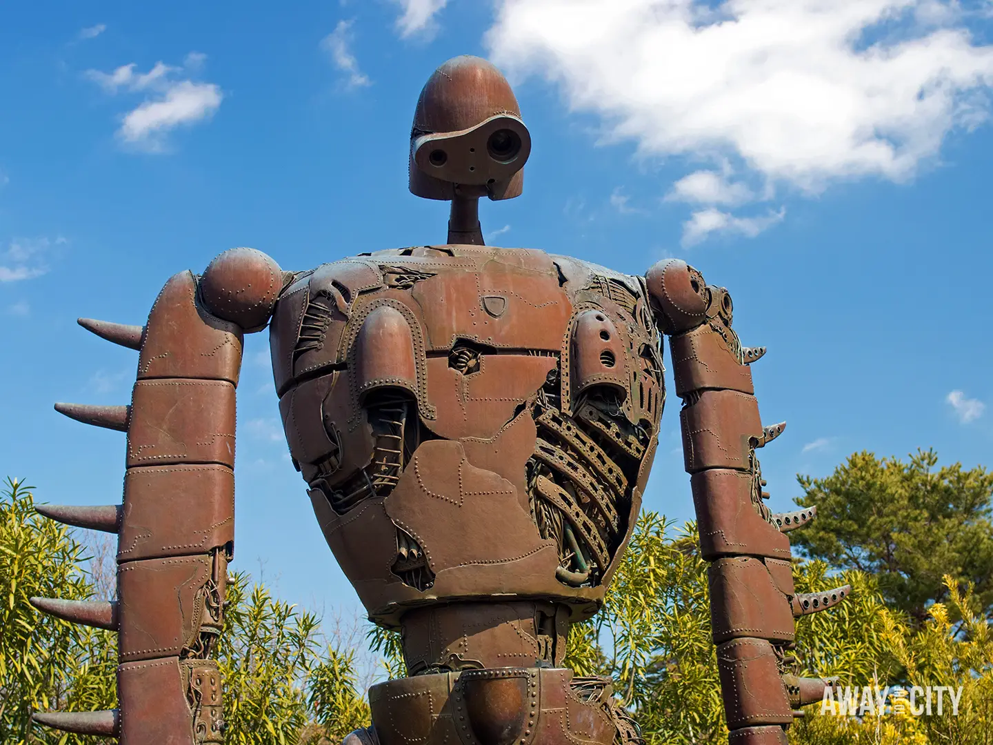 Large rusted robot statue of Laputa Robot Soldier, with exposed mechanical details standing outdoors in front of Ghibli Museum in Tokyo.