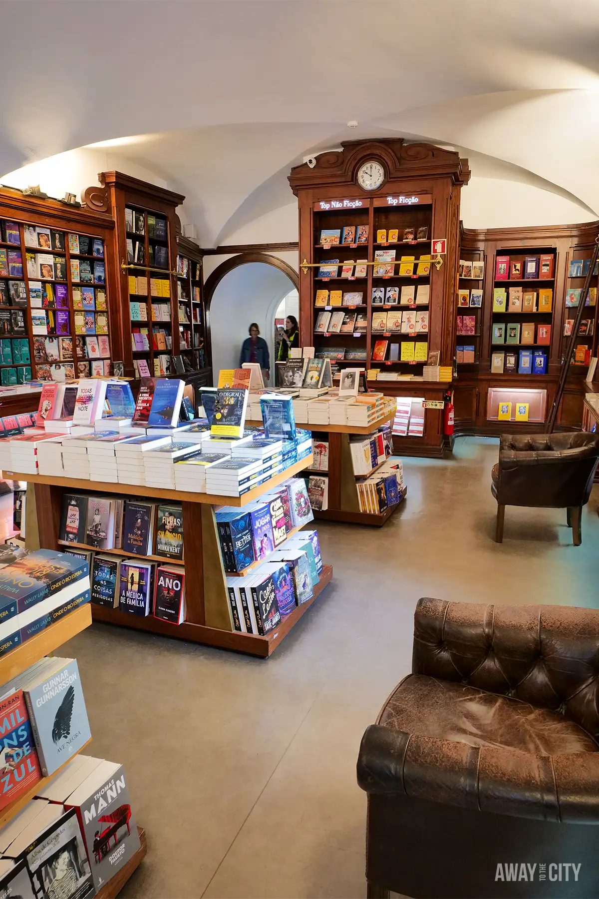 Interior of Livraria Bertrand in Chiado, Lisbon, with wooden bookshelves, display tables and leather armchairs.