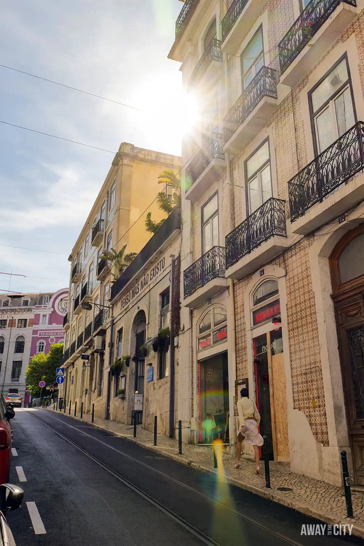 Sunlight shines along Rua Trindade in Chiado, Lisbon, illuminating tiled façades, balconies and a quiet street.