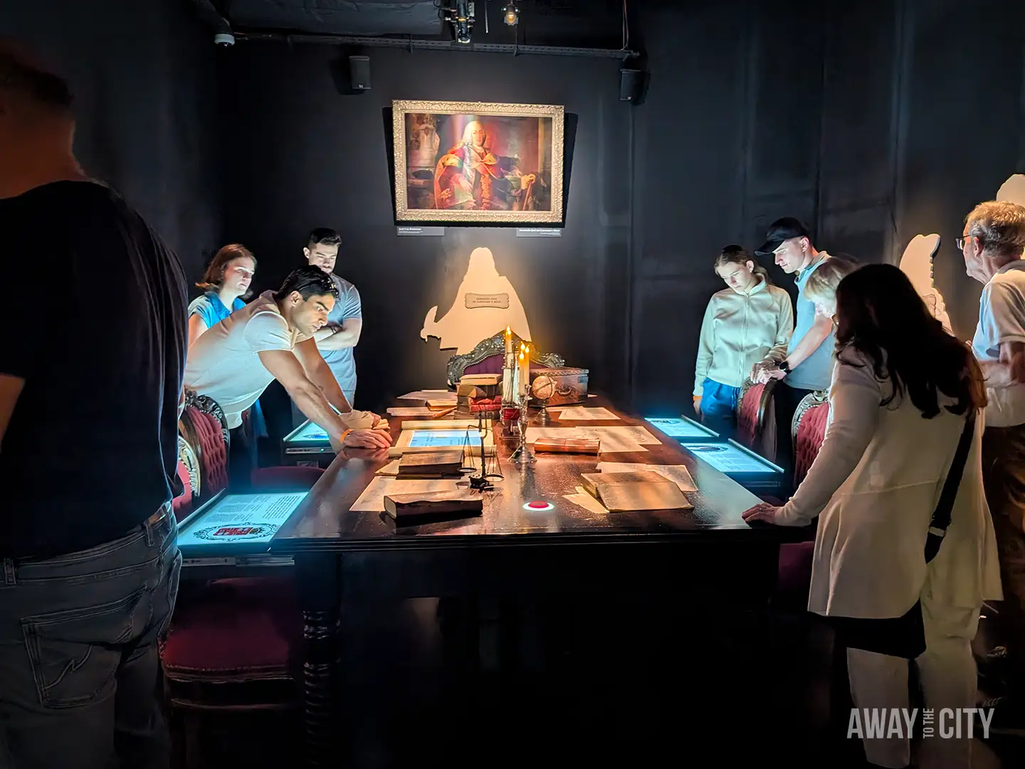 Visitors gathered around an interactive table exhibit inside the Quake Experience in Lisbon, exploring earthquake history displays.