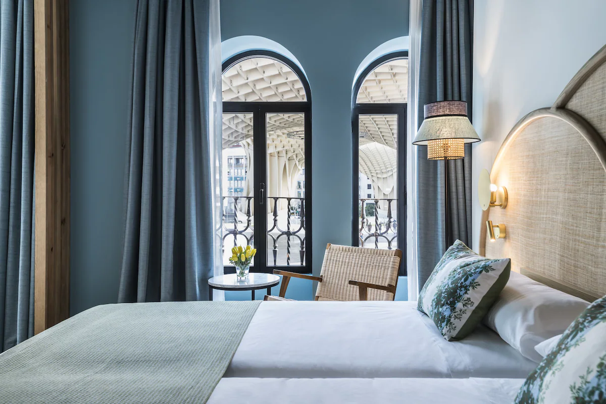 A cosy hotel room in Seville with a view of the Metropol Parasol from arched windows.