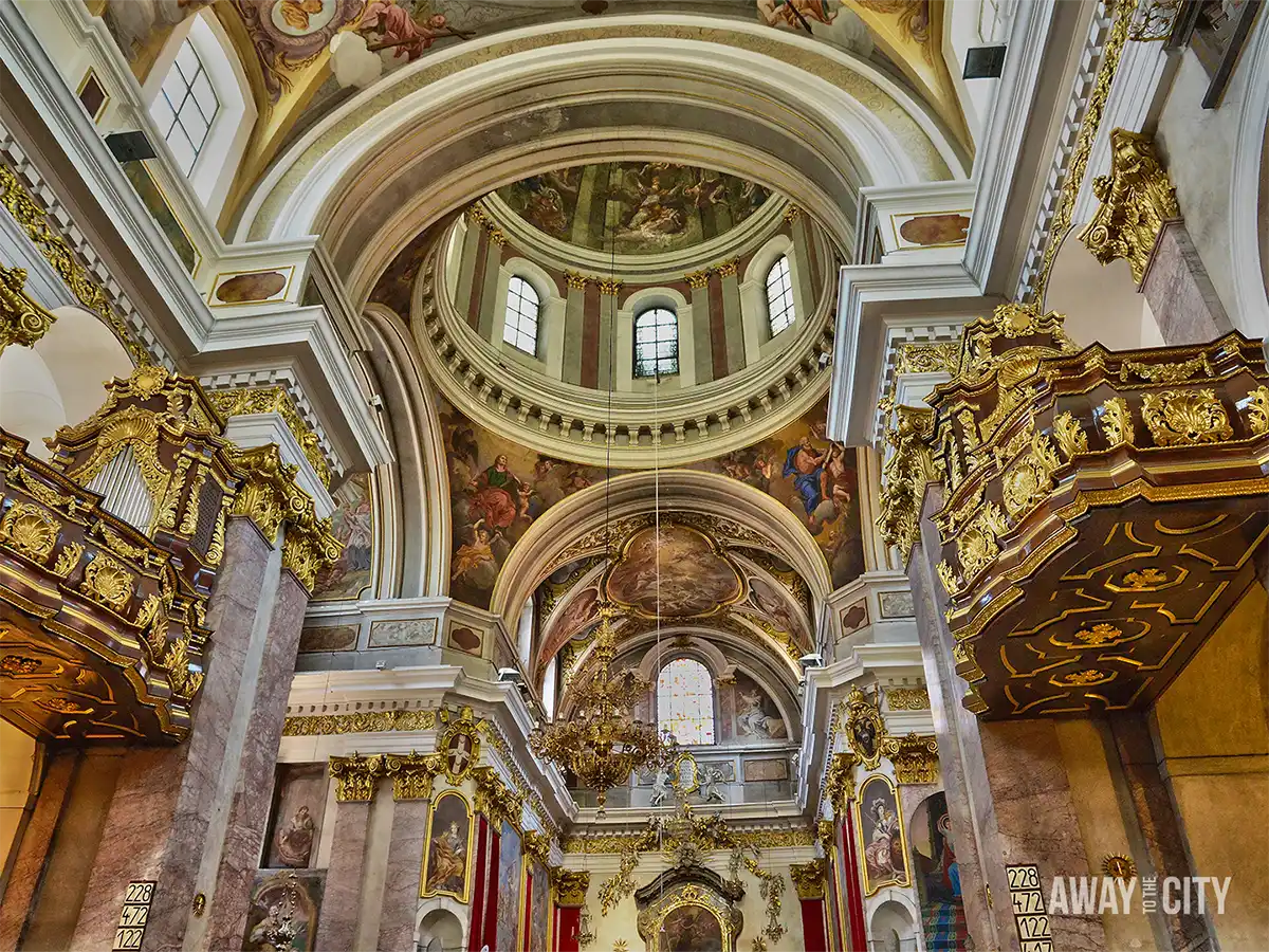 Interior of Cathedral of St Nicholas in Ljubljana with domed ceiling, frescoes, gilded pulpits, chandeliers, and richly decorated Baroque arches.