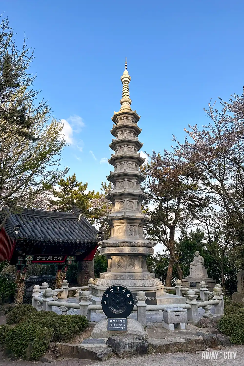 Stone pagoda at Haedong Yonggungsa Temple in Busan, known as the traffic wishing pagoda, surrounded by trees and temple buildings.