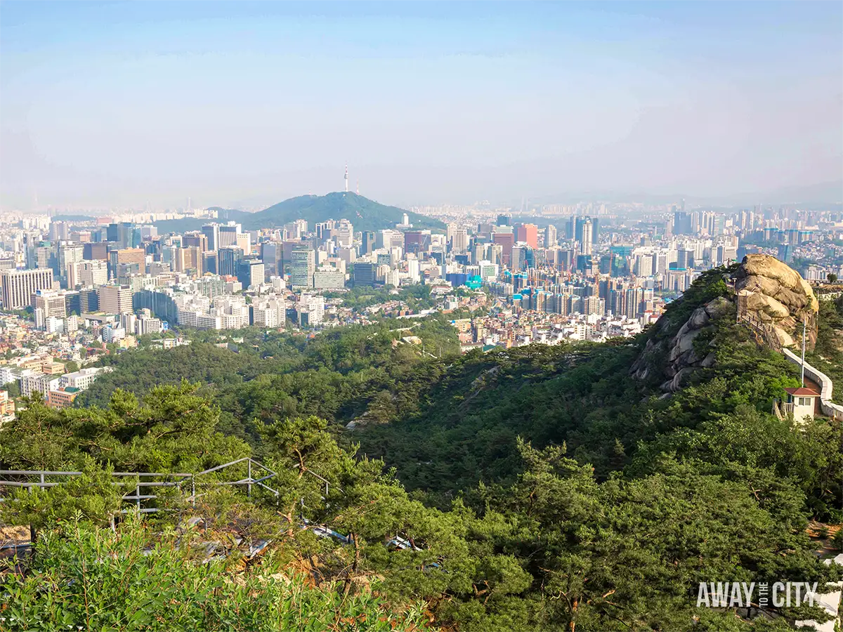 View from Inwangsan Mountain across Seoul’s skyline, with forested hills, rocky outcrops and N Seoul Tower visible in the distance.