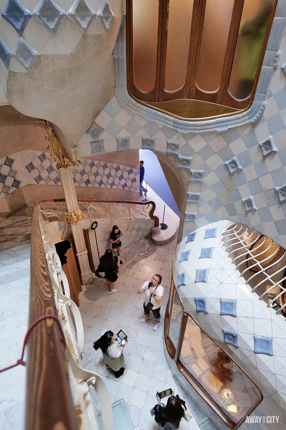 A view of the concierge room in Casa Batlló shows the tiled walls and a curved wooden staircase.