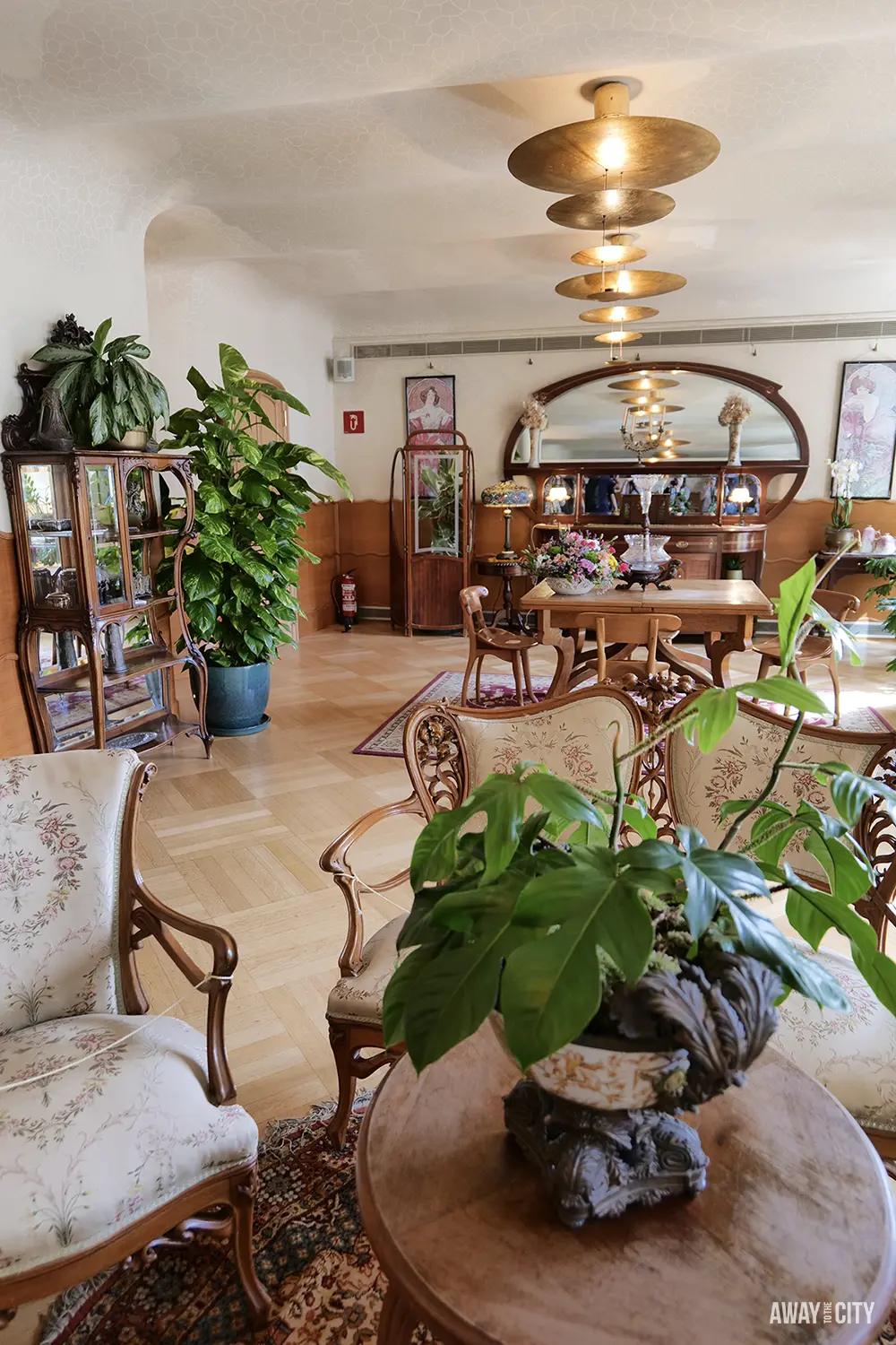 An opulent Art Nouveau sitting room inside Casa Batlló features antique furniture and large potted plants.