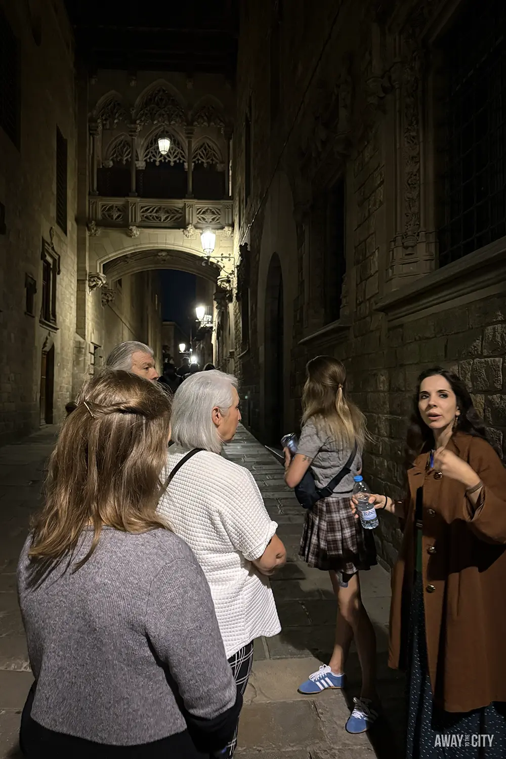 A group of people listening to a guide at night on a narrow cobbled street in Barcelona's Gothic Quarter, one of the most fun things to do in Barcelona.