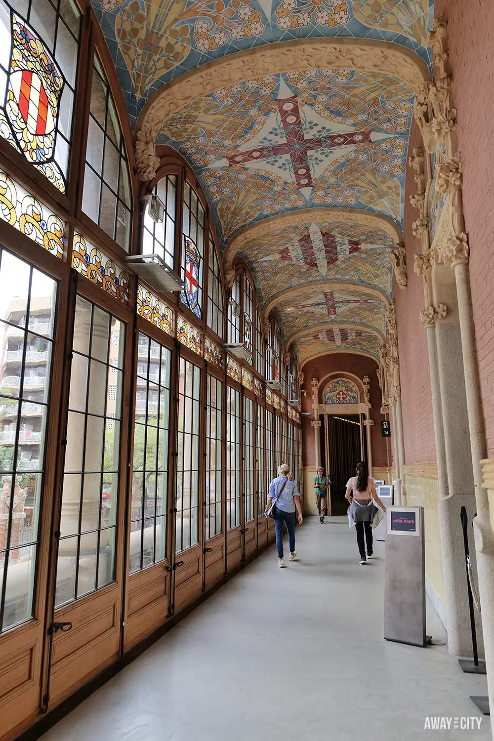 The bright corridor inside the Administration Pavilion at Sant Pau hospital, with stained-glass windows and an ornate, vaulted ceiling.