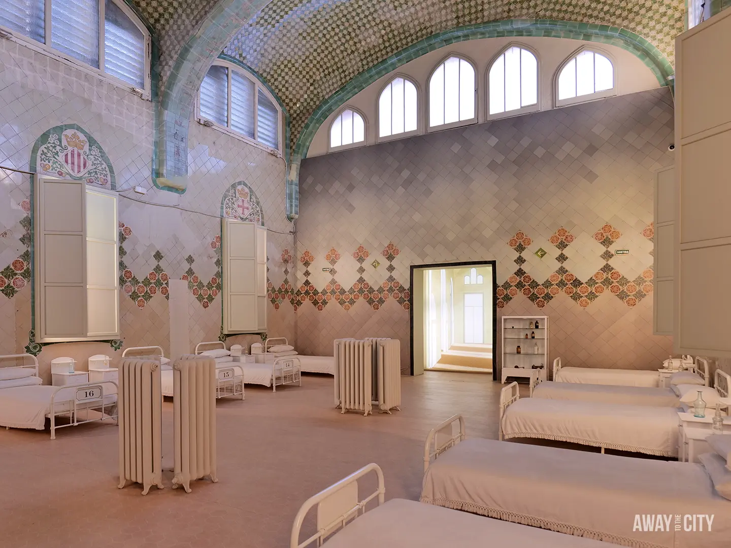 The restored interior of a ward in the Sant Rafael Pavilion at Sant Pau hospital, featuring beds and decorative tilework, a true hidden gem in Barcelona, Spain.