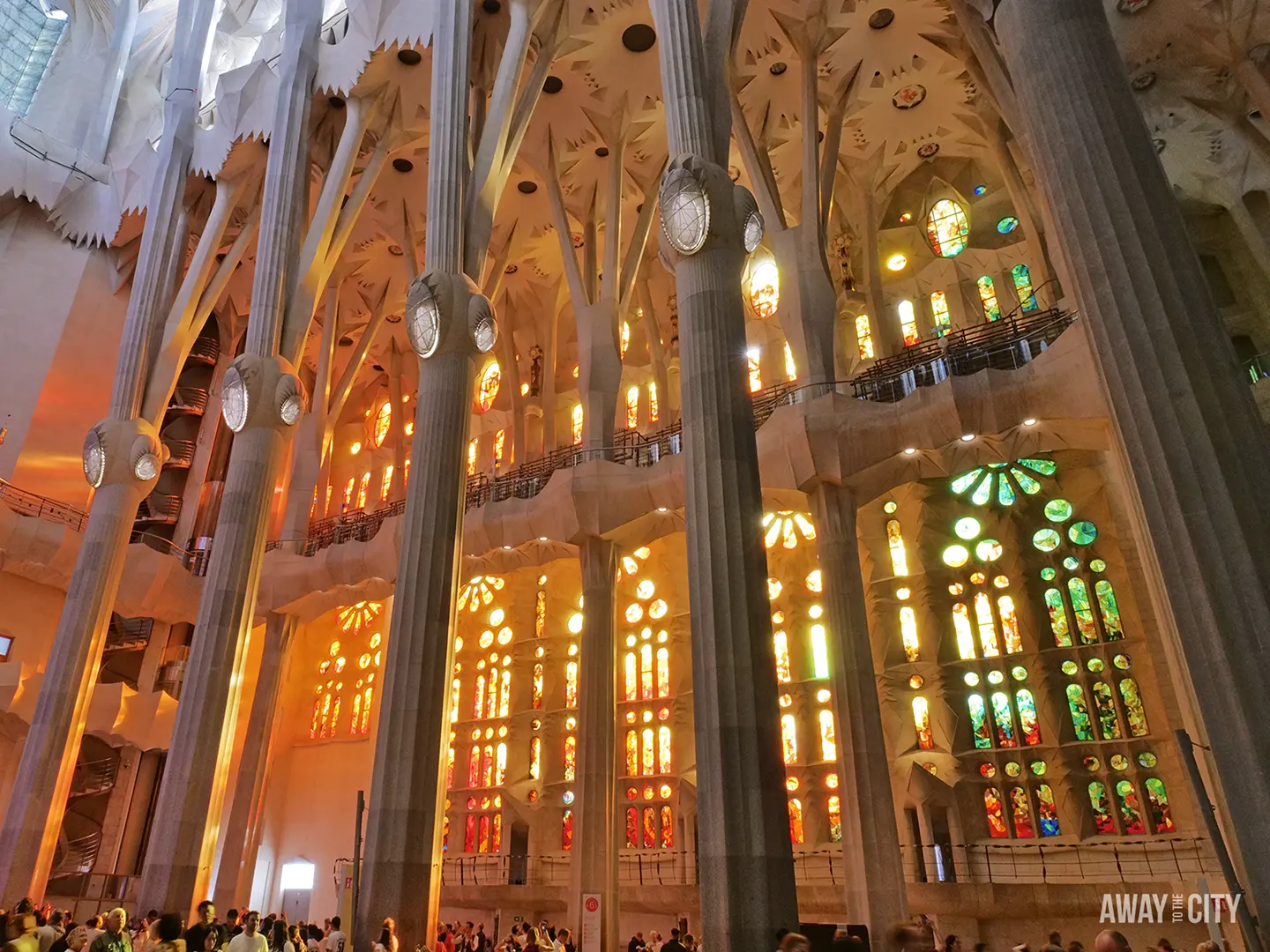 Sunlight streams through the colourful, geometric stained-glass windows illuminating the tree-like columns of the Sagrada Família, one of the best things to do in Barcelona, Spain.
