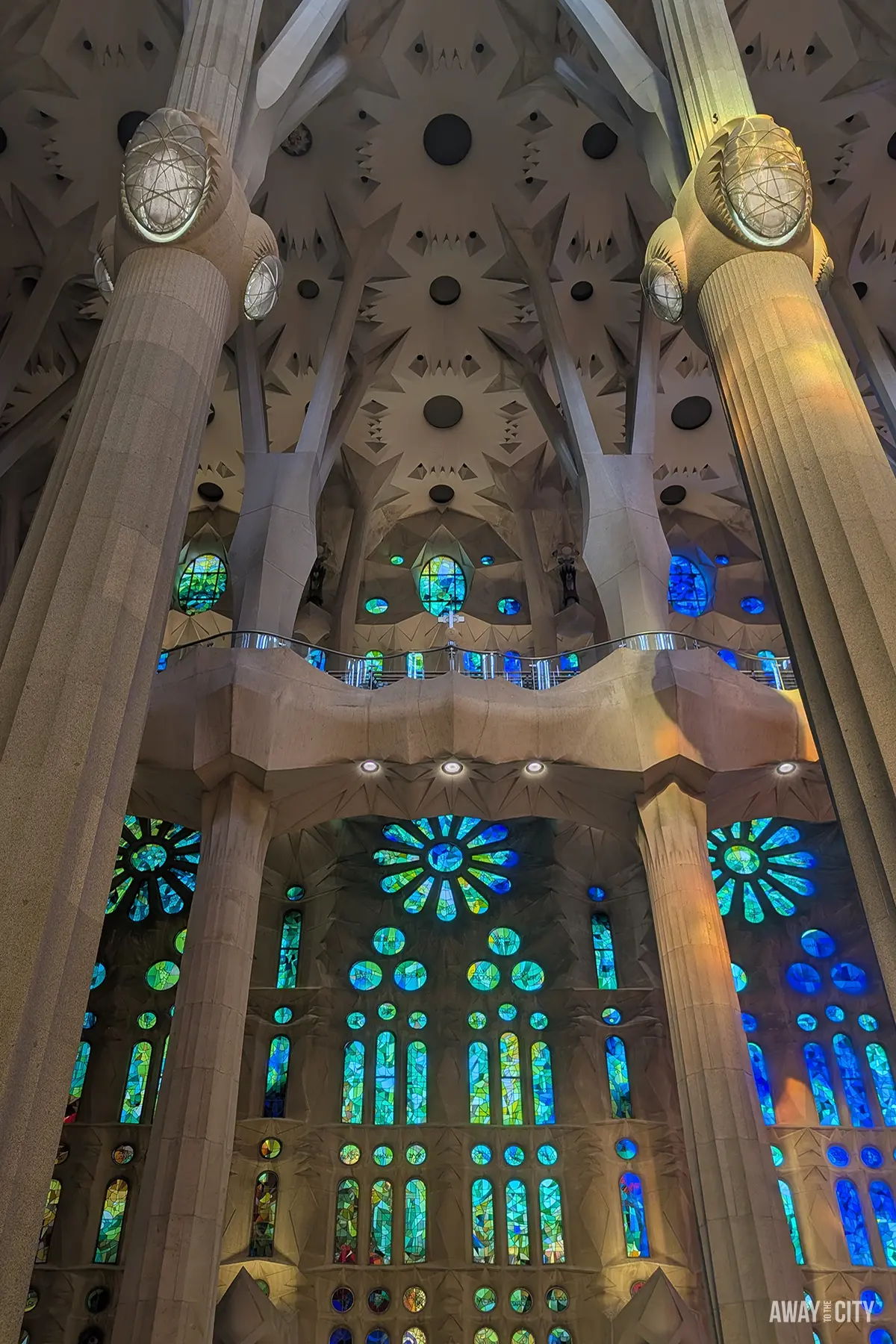 Blue, green, and red light filters through the recessed stained glass of the Sagrada Família's high wall.