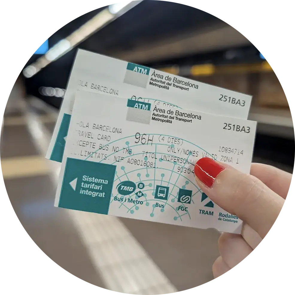 A person with red nail varnish holds two Hola Barcelona Travel Cards for the city's public transport system.