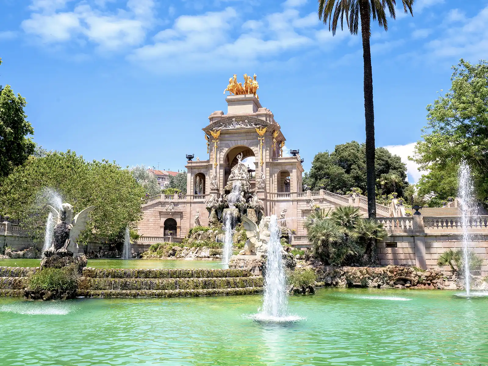 The impressive Cascada Monumental fountain in Parc de la Ciutadella on a sunny day, with jets of water and the golden chariot on top.