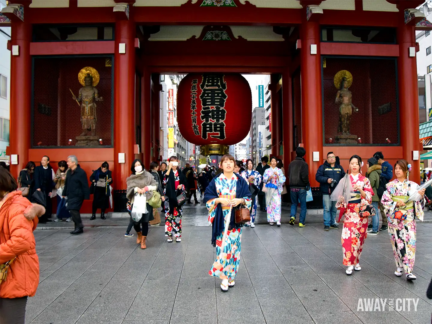 Kaminarimon Gate at Sensō-ji Temple in Tokyo, featuring its enormous red lantern beneath the gate as visitors and people in colourful kimono gather outside.