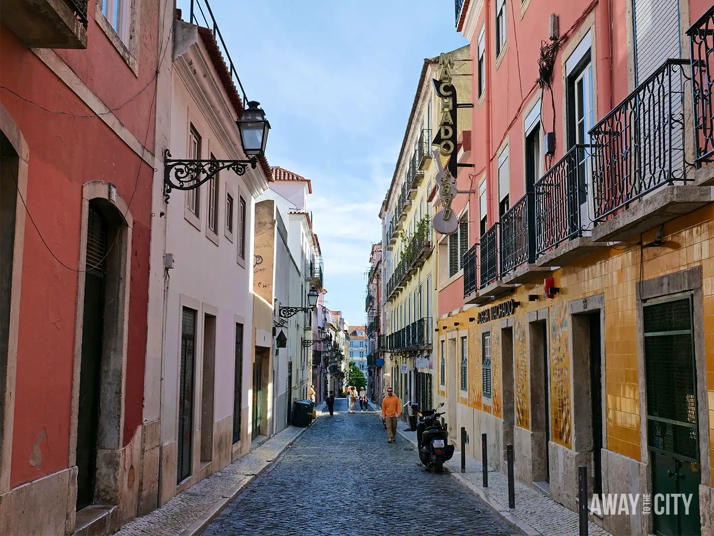 Narrow cobbled street in Lisbon lined with colourful traditional buildings, which is one of the destinations perfect for a free trip.