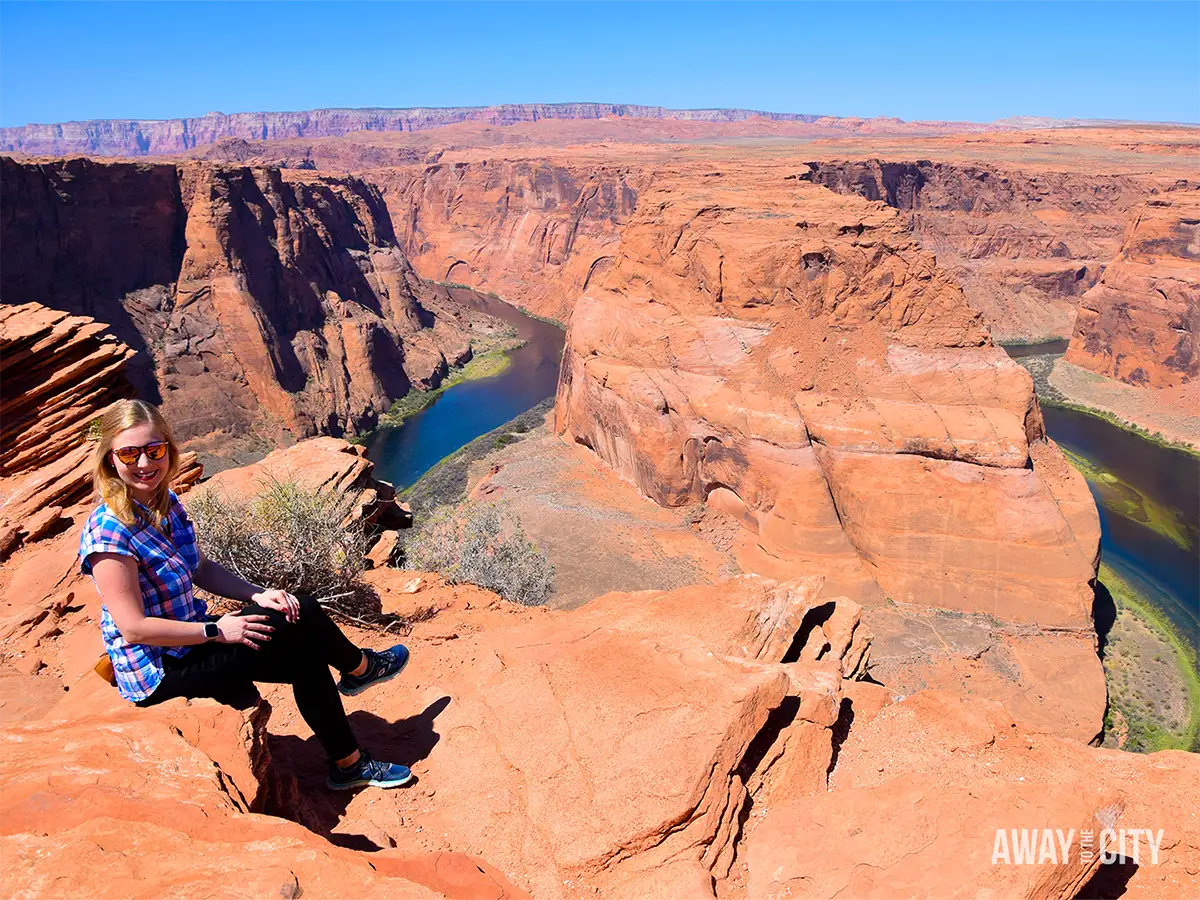 Person sitting on red sandstone cliffs overlooking Horseshoe Bend near Page, Arizona, one of the best destinations to travel for free.