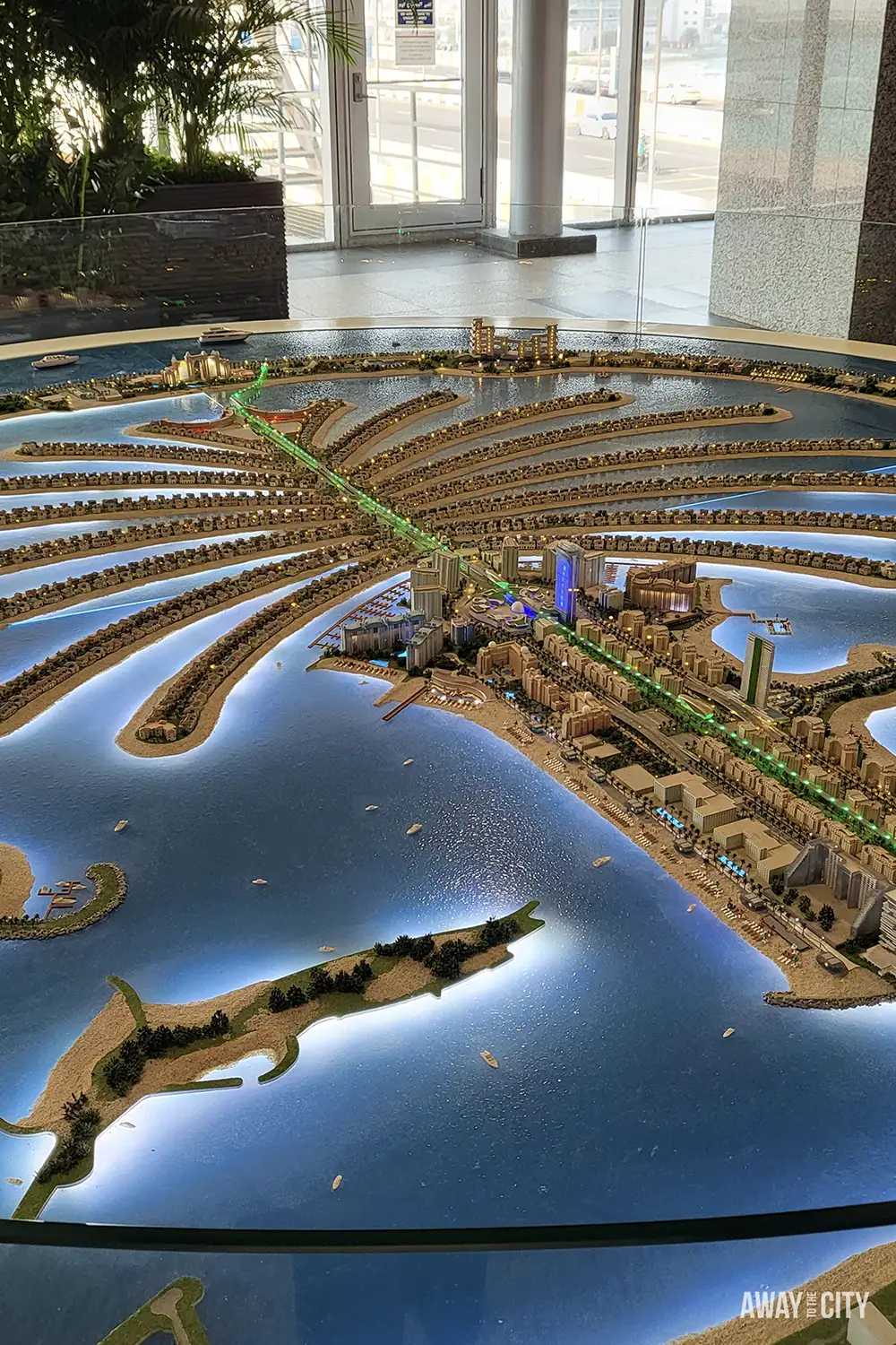 Indoor scale model of Palm Jumeirah with illuminated fronds, monorail and waterfront buildings.