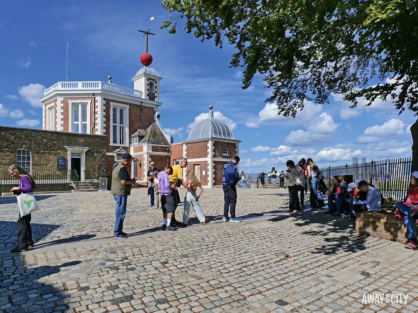 The courtyard of the Royal Observatory in Greenwich, with tourists posing on the Meridian line, one of the many unique things to do in London.